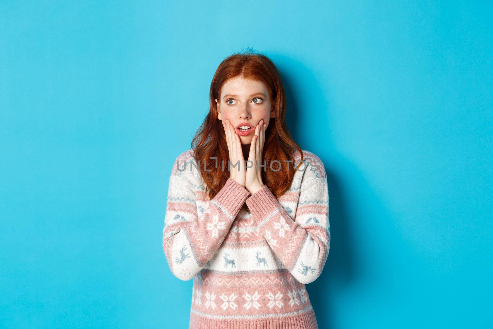 Image of shocked and impressed redhead girl realise something, staring left amazed, standing over blue background by Benzoix