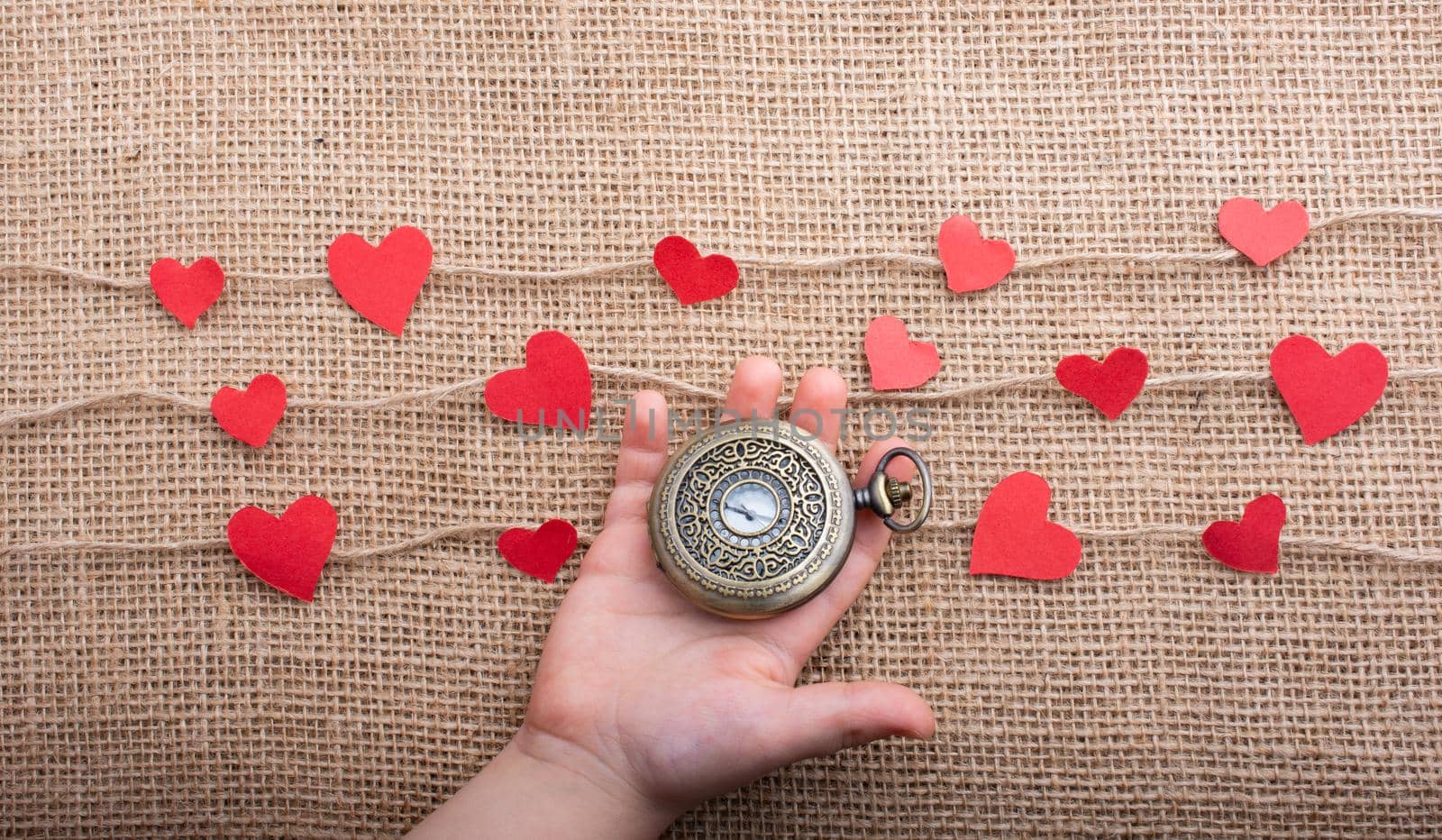 Love concept with pocket watch and  paper hearts on threads