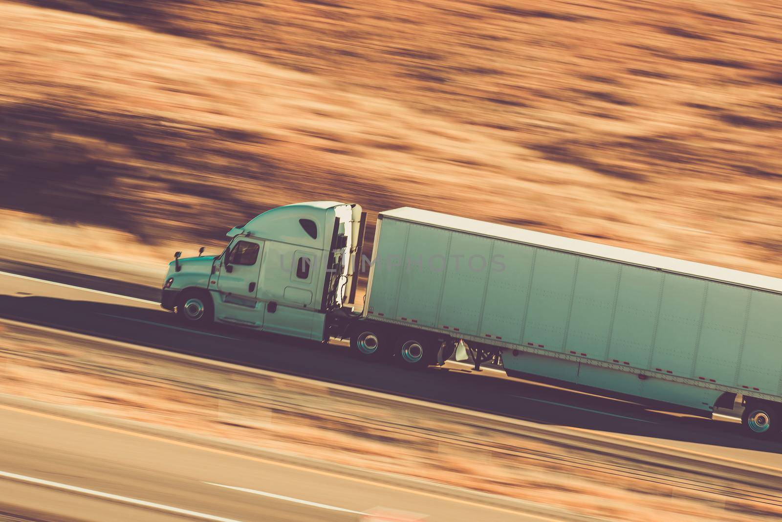 Cross Country Semi Truck Transport Concept. American Semi Trailer Speeding on a Highway. Real Motion Blur. Transportation and Freight Theme.