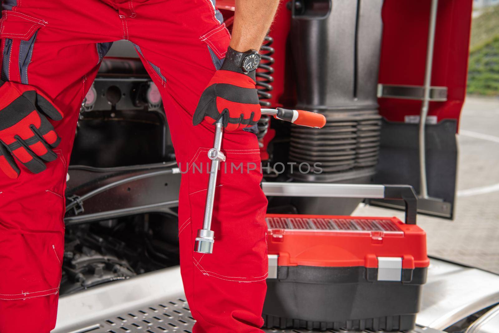 Automotive Mechanic with Large Wrench Standing on a Semi Truck Tractor. Lower Body Part Close Up. Trucking Company Theme.