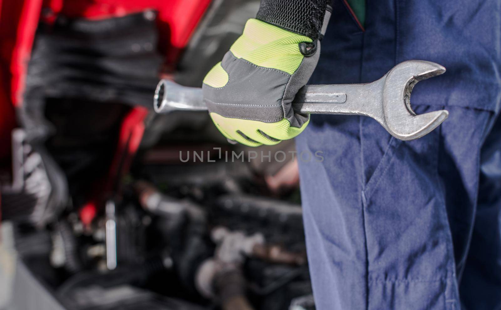 Semi Trucks Mechanic with a Large Wrench in His Hand Close Up Photo. Heavy Duty Transportation Mechanical Issues Theme.