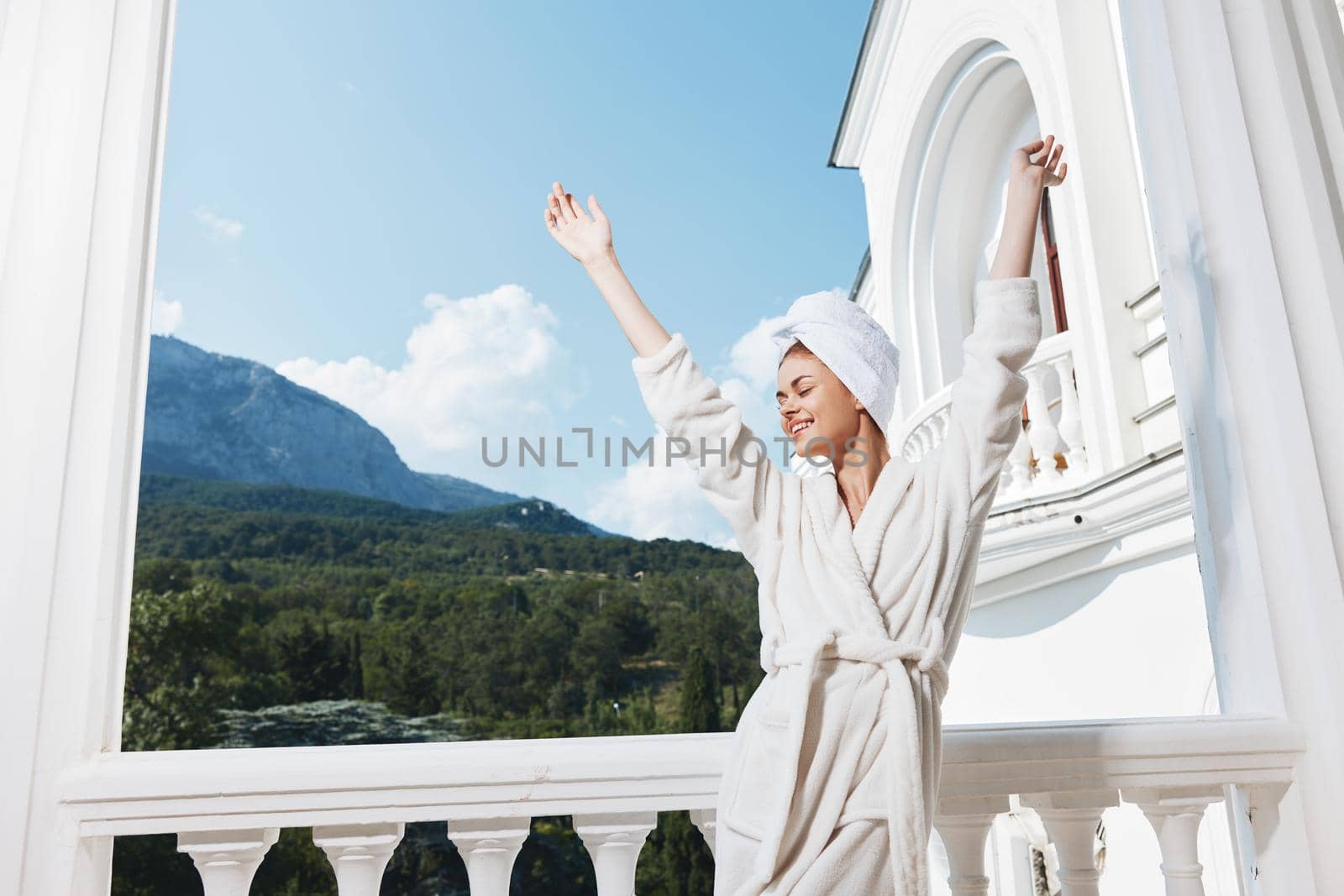 Attractive young woman posing against the backdrop of mountains on the balcony architecture unaltered. High quality photo