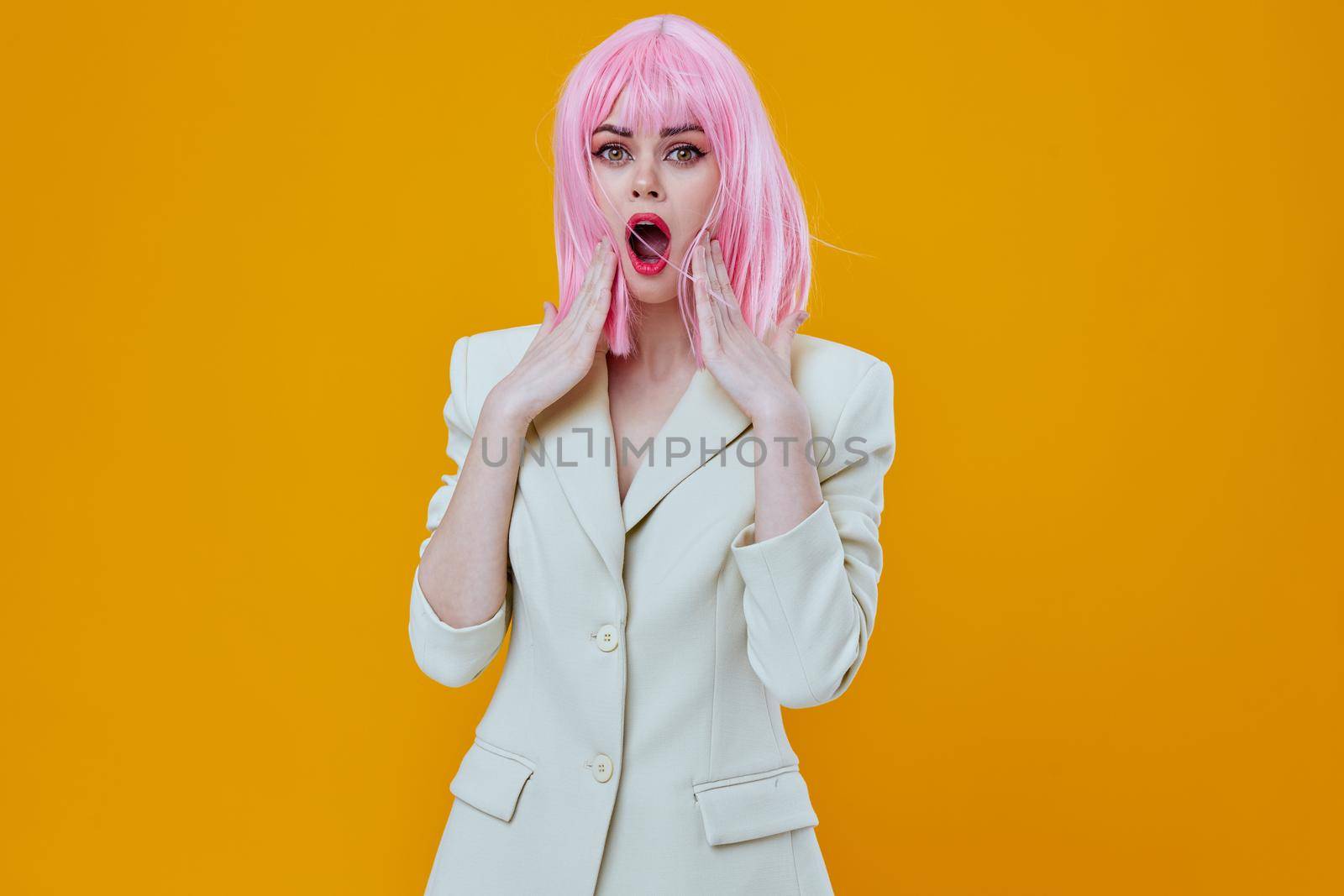 Woman in white suit pink wig posing on yellow background. High quality photo