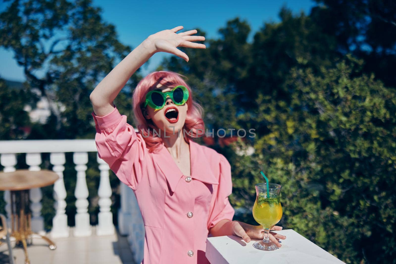 cheerful woman in pink dress outdoors with cocktail Happy female relaxing. High quality photo