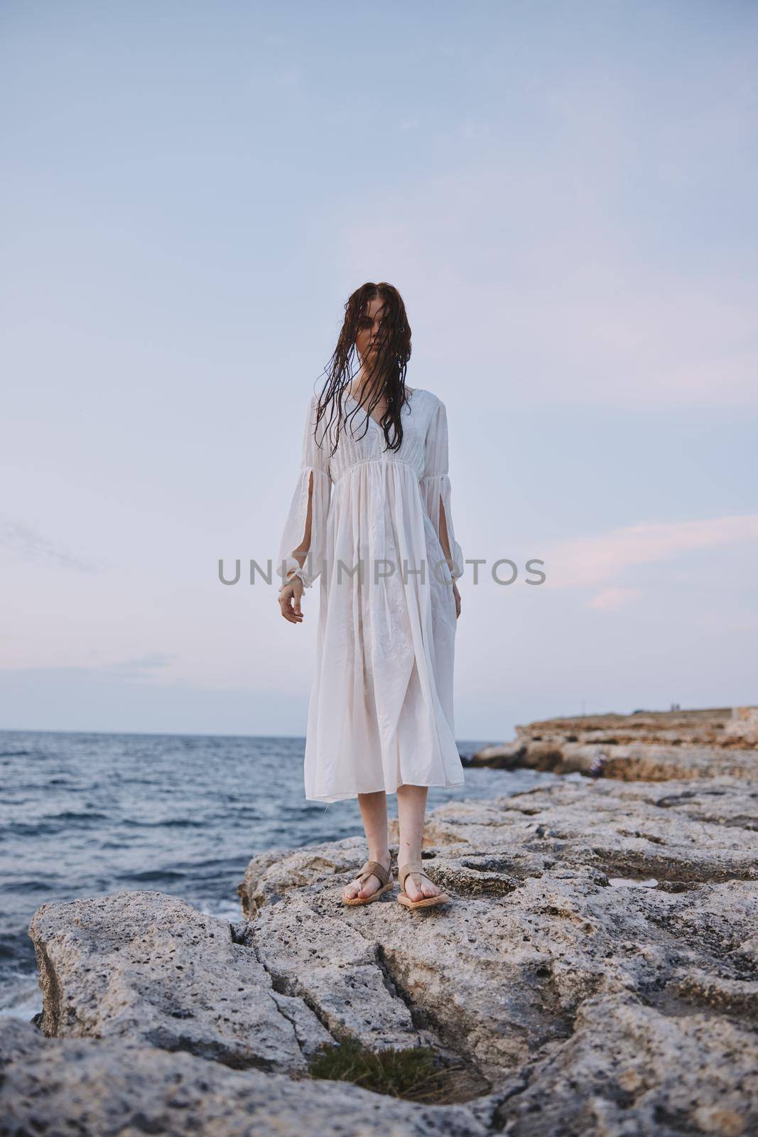 Woman in white dress rocks ocean nature freedom unaltered. High quality photo