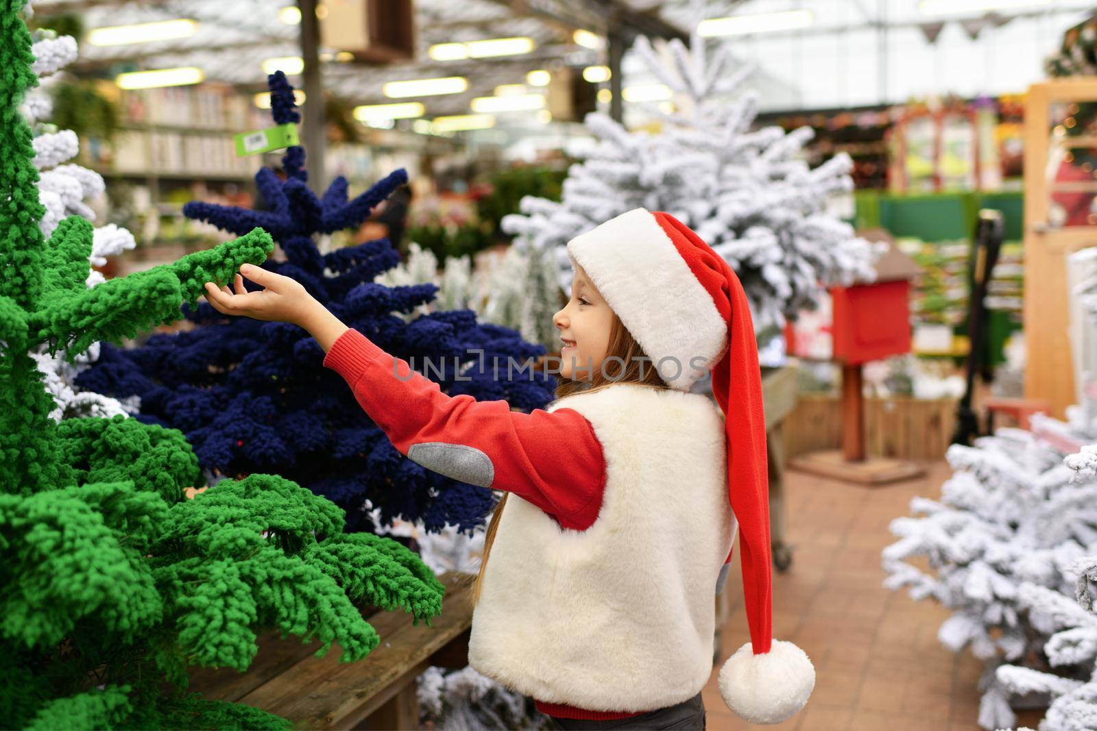 A girl and a white christmas artificial trees for sale at a shop