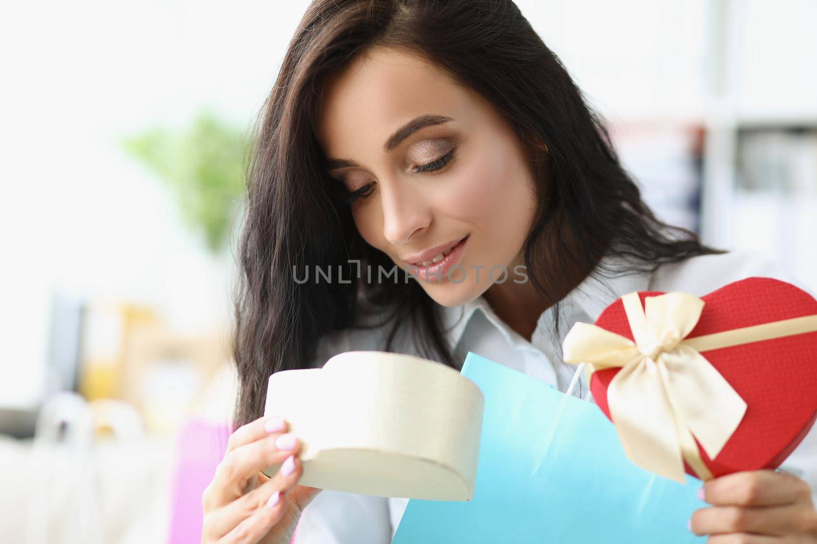 Portrait of brunette female open festive box and search for gift inside, curious look. Present for birthday, anniversary or any event. Surprise concept