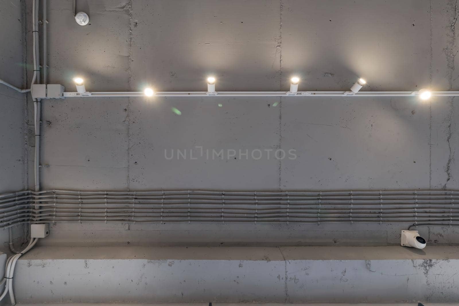 Abstract loft interior of concrete grey ceiling with air ventilation and security camera. Interior architecture and ceiling design of industrial loft building decorated with modern lamps by panophotograph