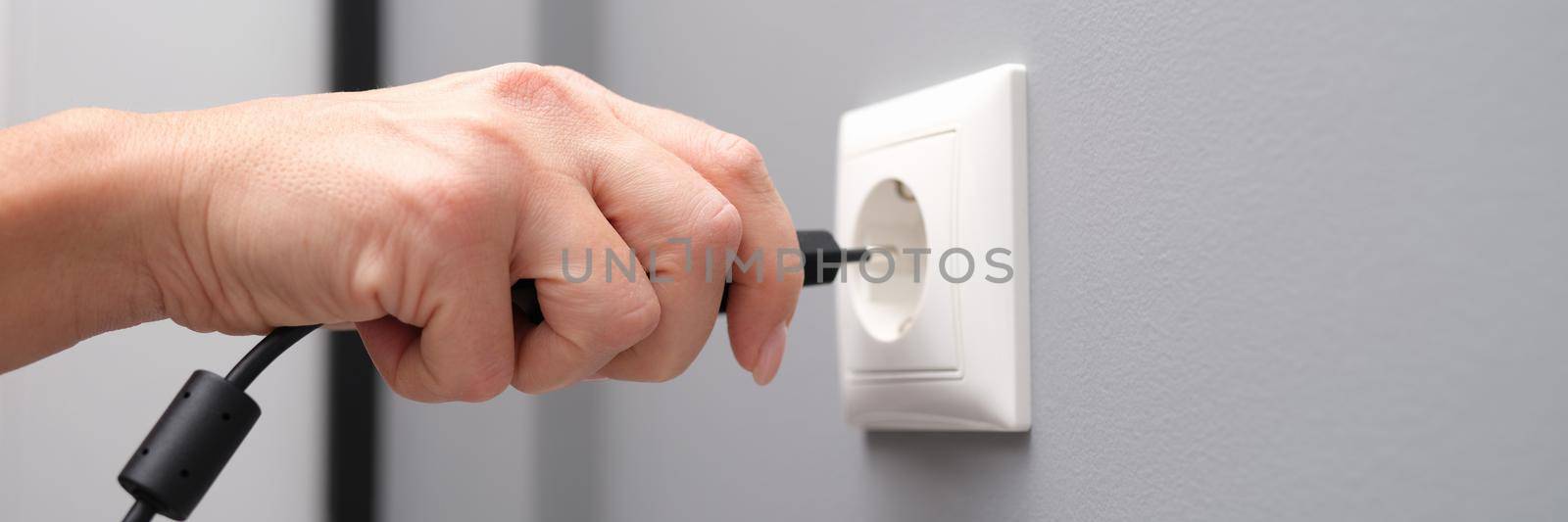 Woman hand inserts an electrical plug into outlet closeup by kuprevich