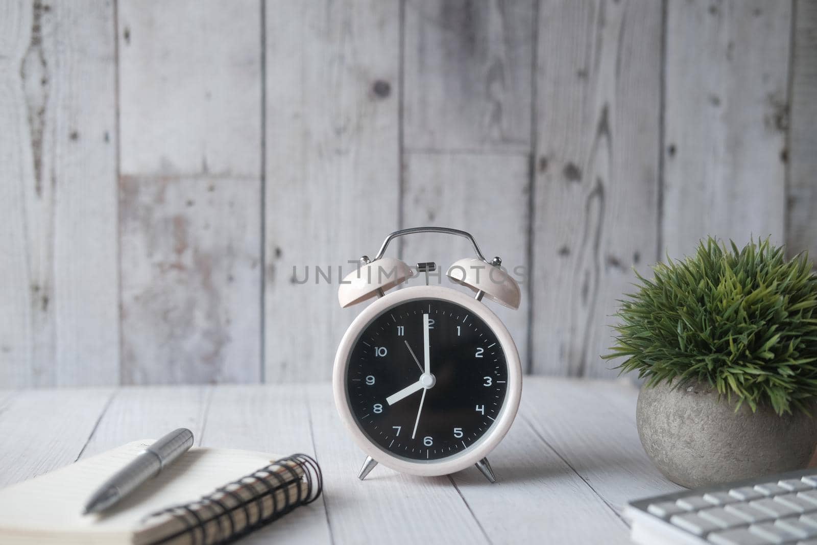 alarm clock ,notepad and pen on table .
