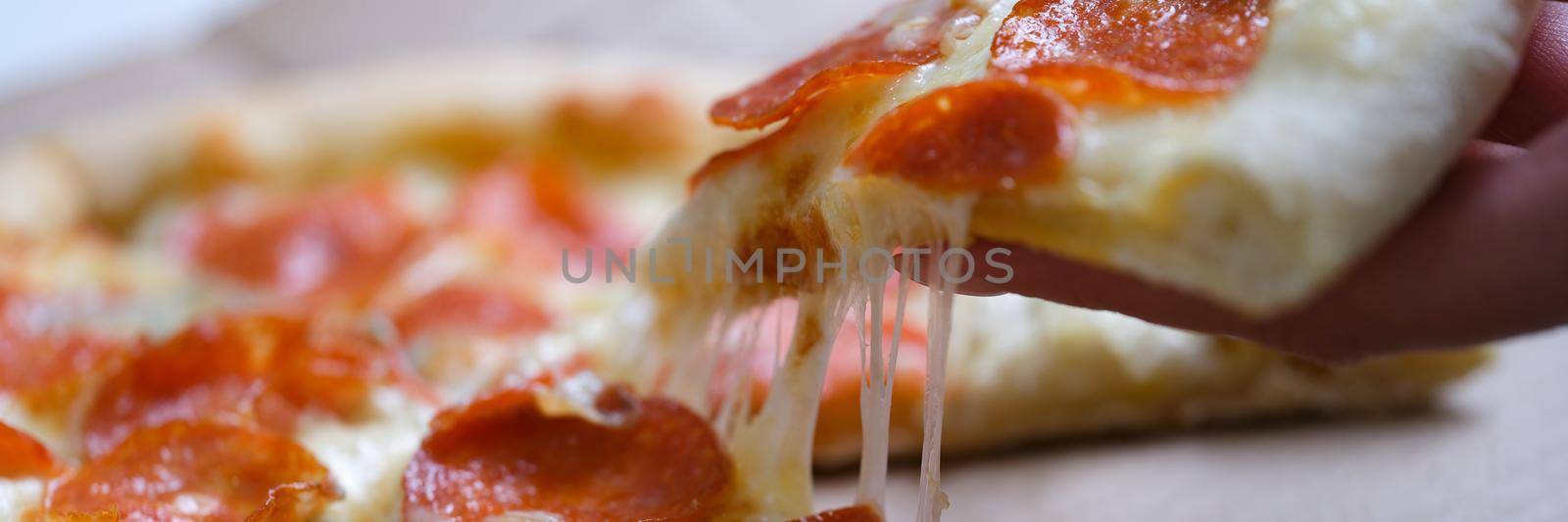 Woman holding piece of delicious hot pizza over box closeup by kuprevich