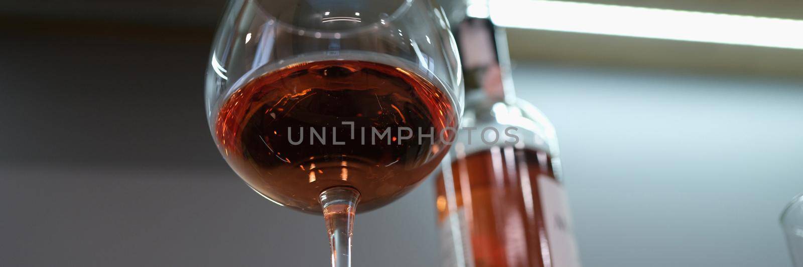 Glass with poured alcohol and bottle is on table. Drinking alcoholic drinks concept