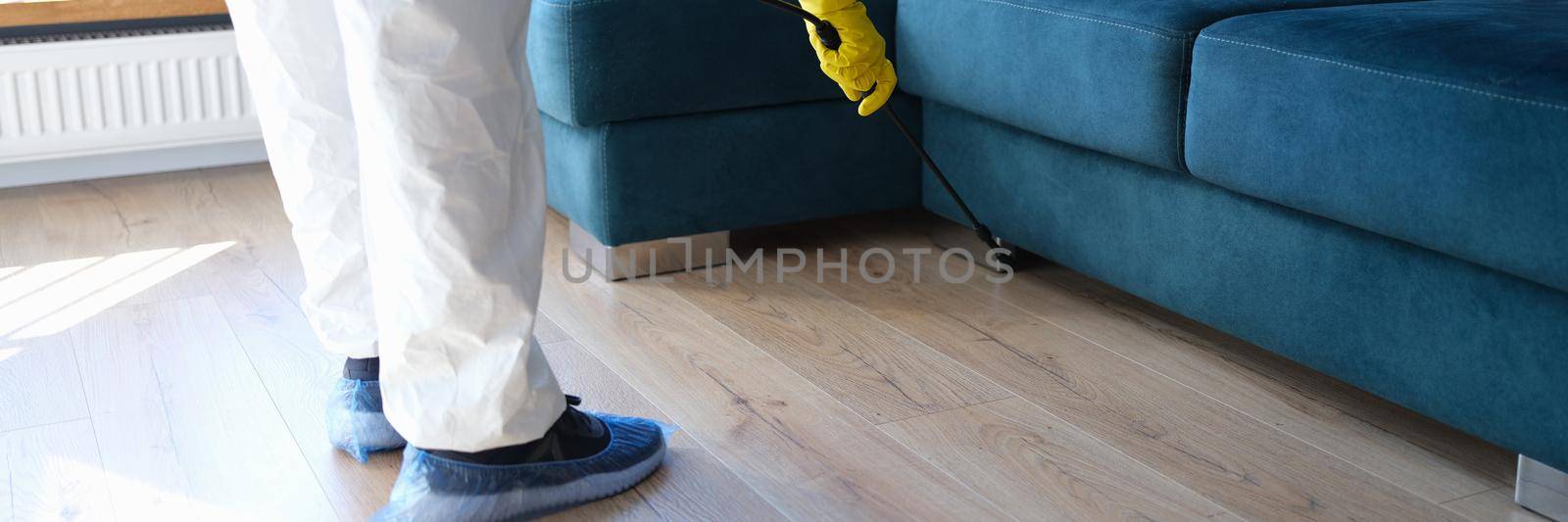 Person in protective suit and gloves is treating room from painful bacteria. Disinfection of premises concept