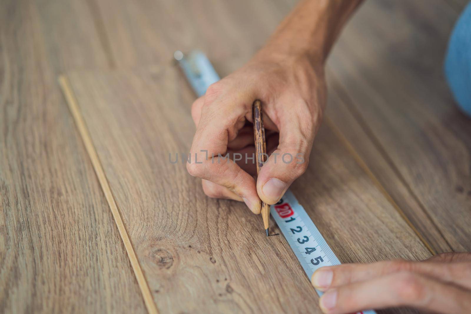 Man installing new wooden laminate flooring on a warm film floor. Infrared floor heating system under laminate floor by galitskaya