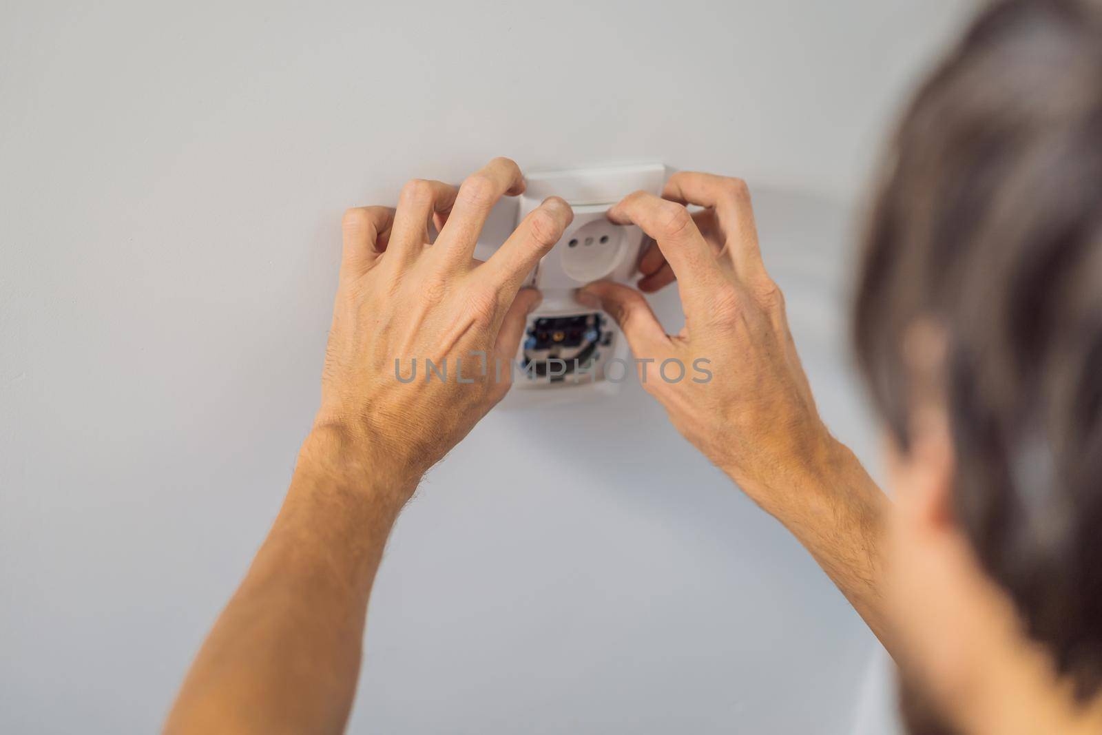 Master electrician installs a socket in the house.