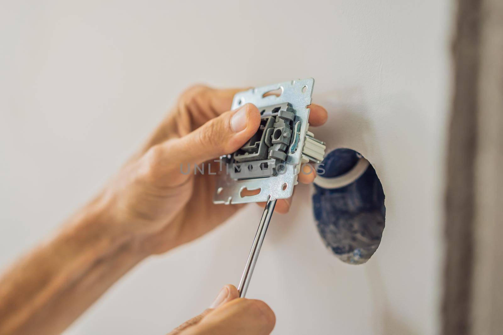 Master electrician installs a socket in the house.