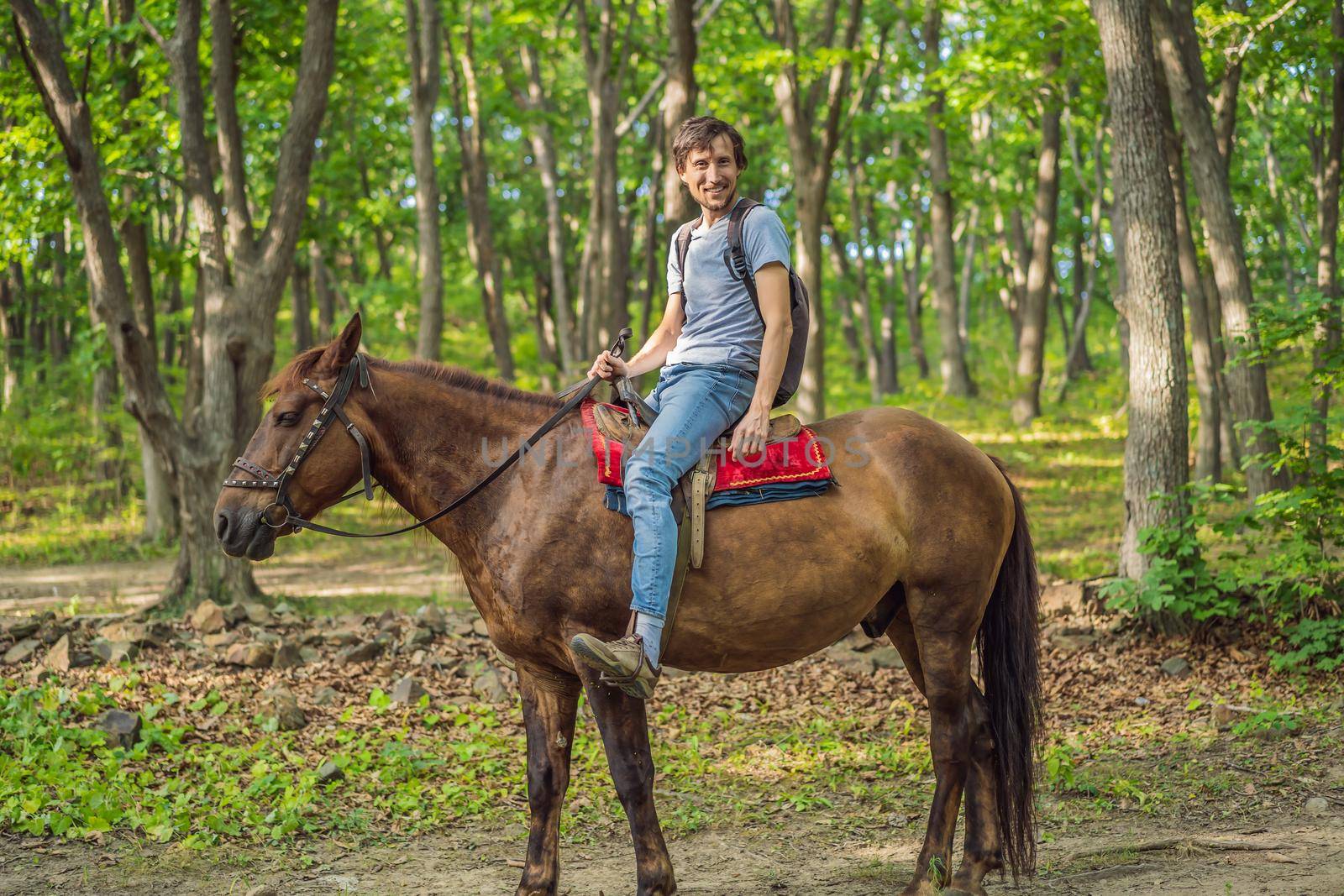 handsome man ride on the black horse in green forest.