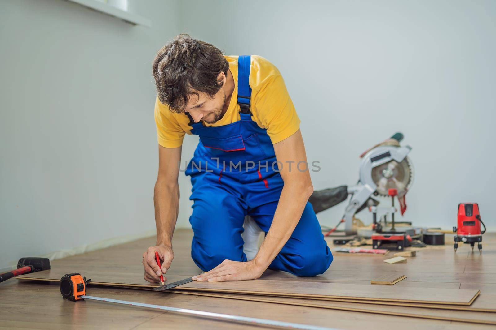 Man installing new wooden laminate flooring on a warm film floor. Infrared floor heating system under laminate floor.