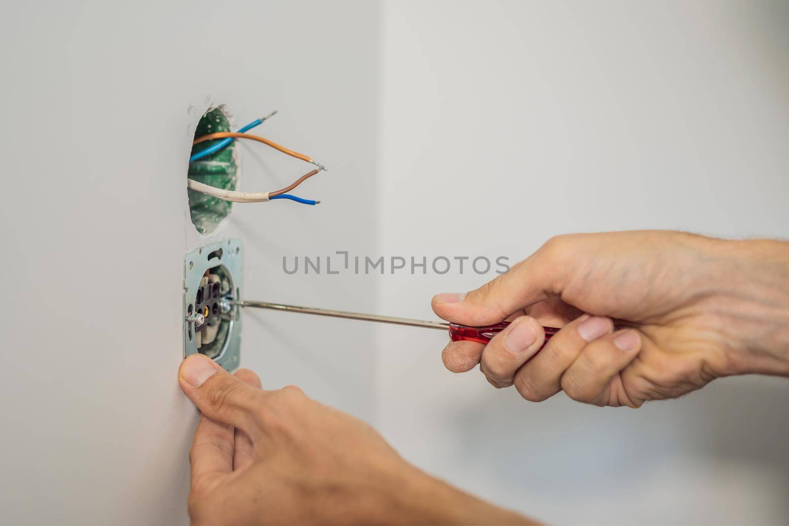 Master electrician installs a socket in the house.