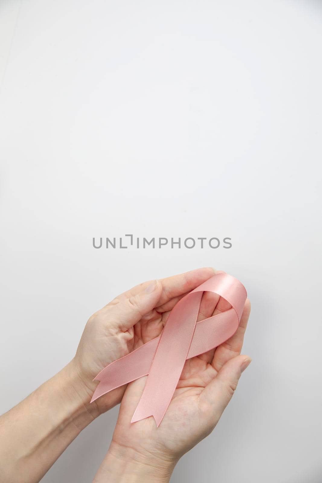 Woman holding pink ribbon on gray background, top view. Breast cancer awareness concept, Female health care concept copy space space for text