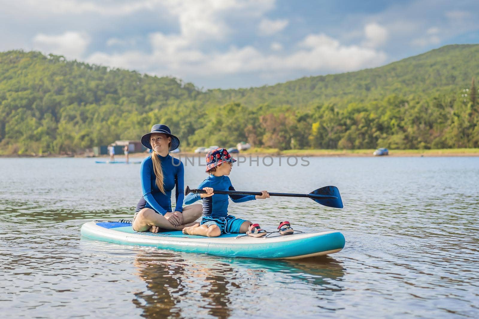 happy family of two, mother and son, enjoying stand up paddling during summer vacation by galitskaya