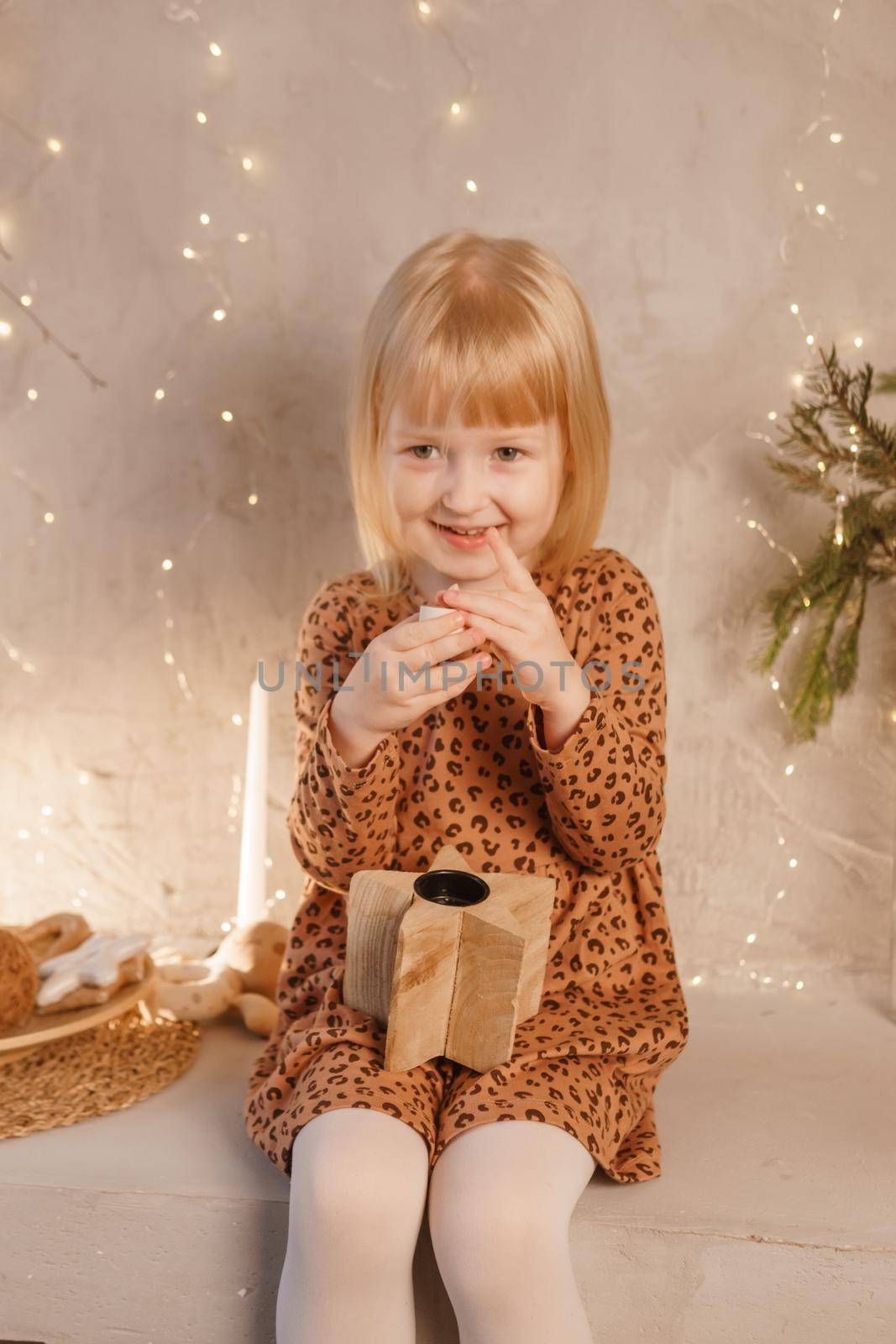 A girl is playing on Christmas Eve in a beautiful house decorated for the New Year holidays. Scandinavian-style interior with live fir trees and a wooden staircase.