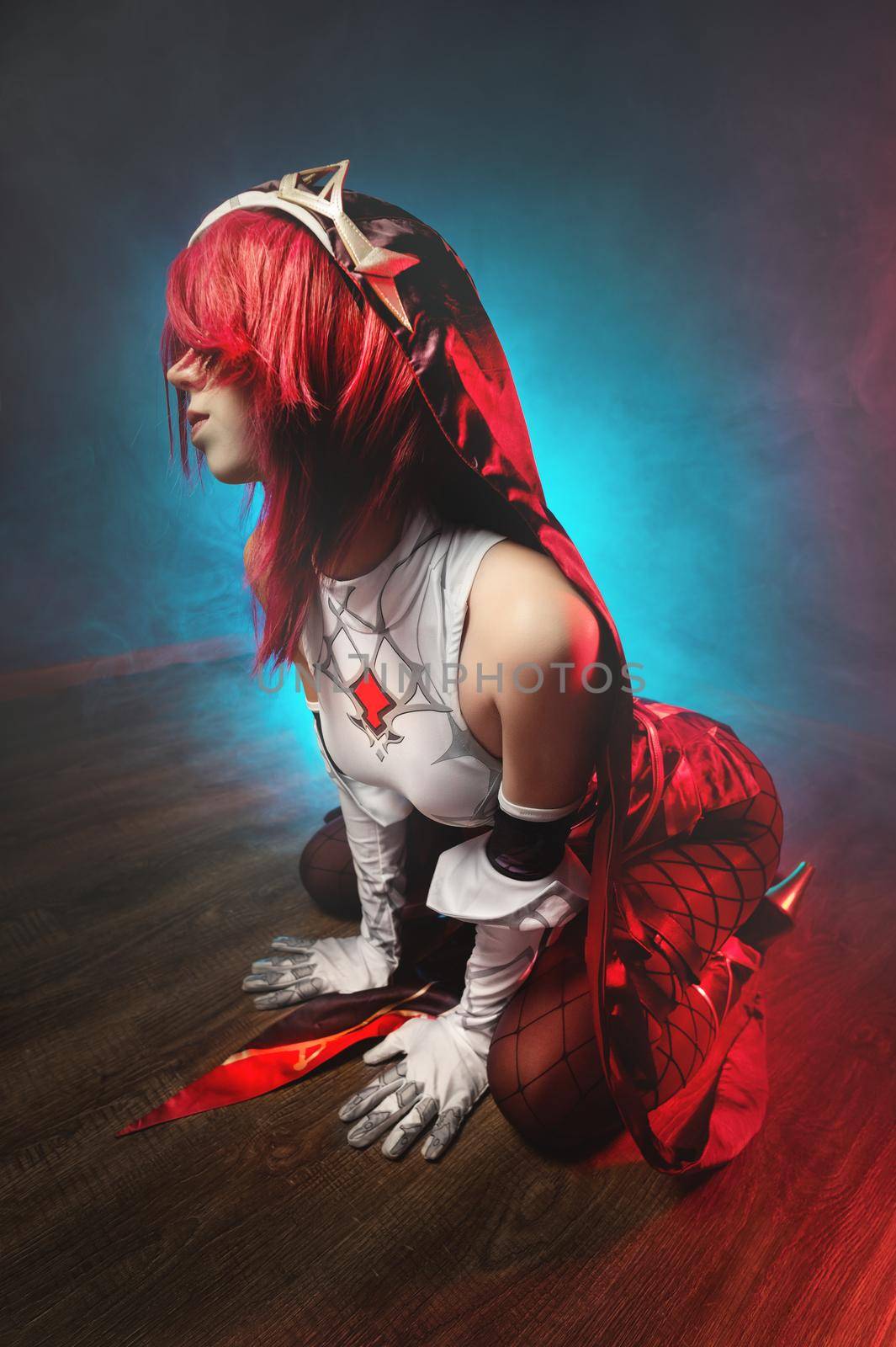 Cosplay. Studio portrait of attractive sexy young woman in anime rosary costume with red hairs and white gloves. Sexual pose on the floor in colored light.