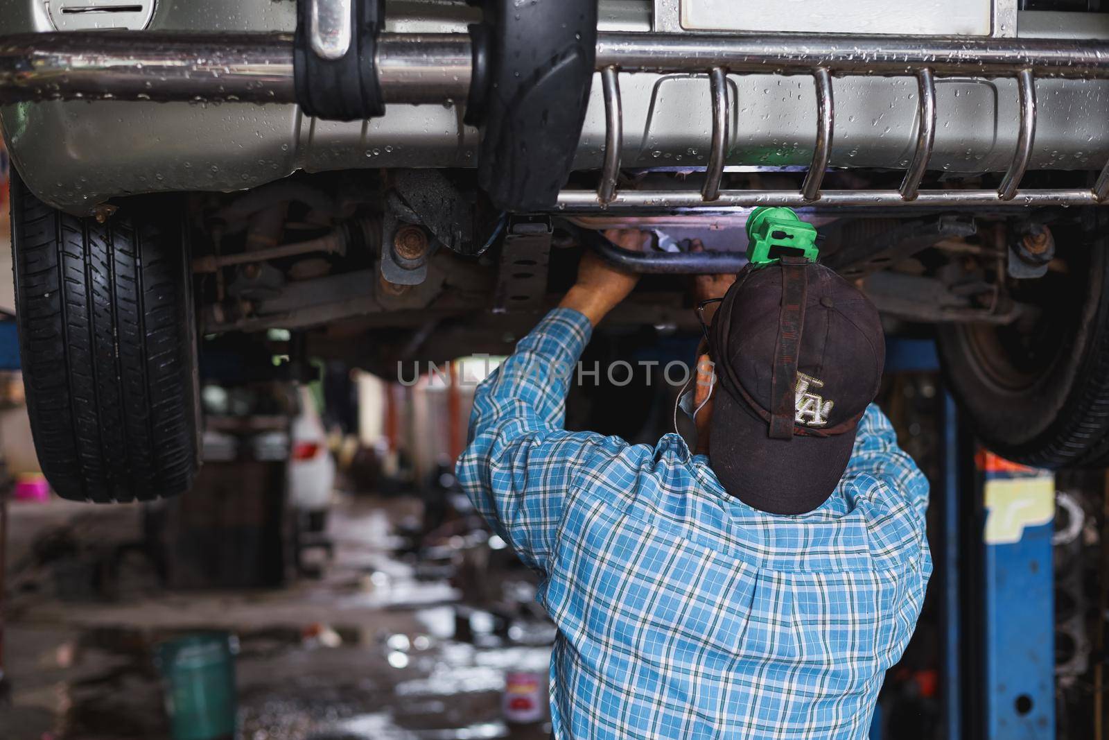 The mechanic is checking the undercarriage of the car.