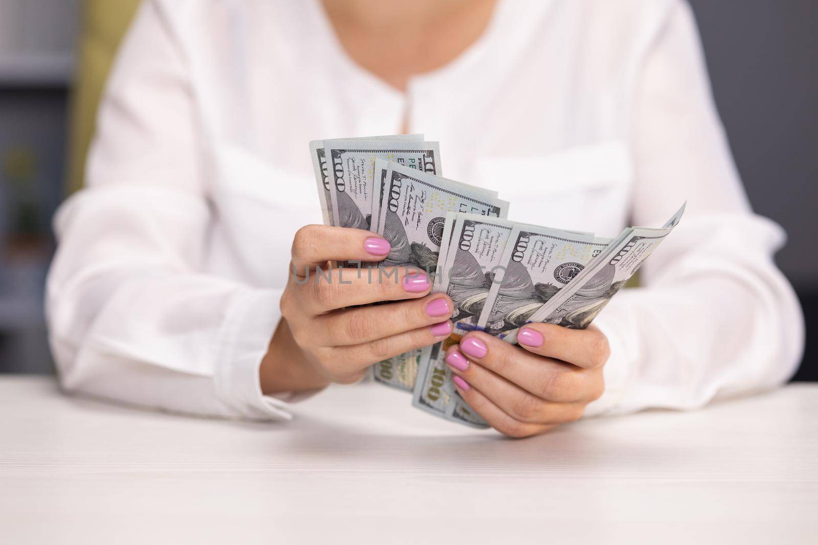 Close-up female caucasian hands counting money. Unrecognizable young woman calculating cash dollars indoors at home. Finance and richness concept. by uflypro