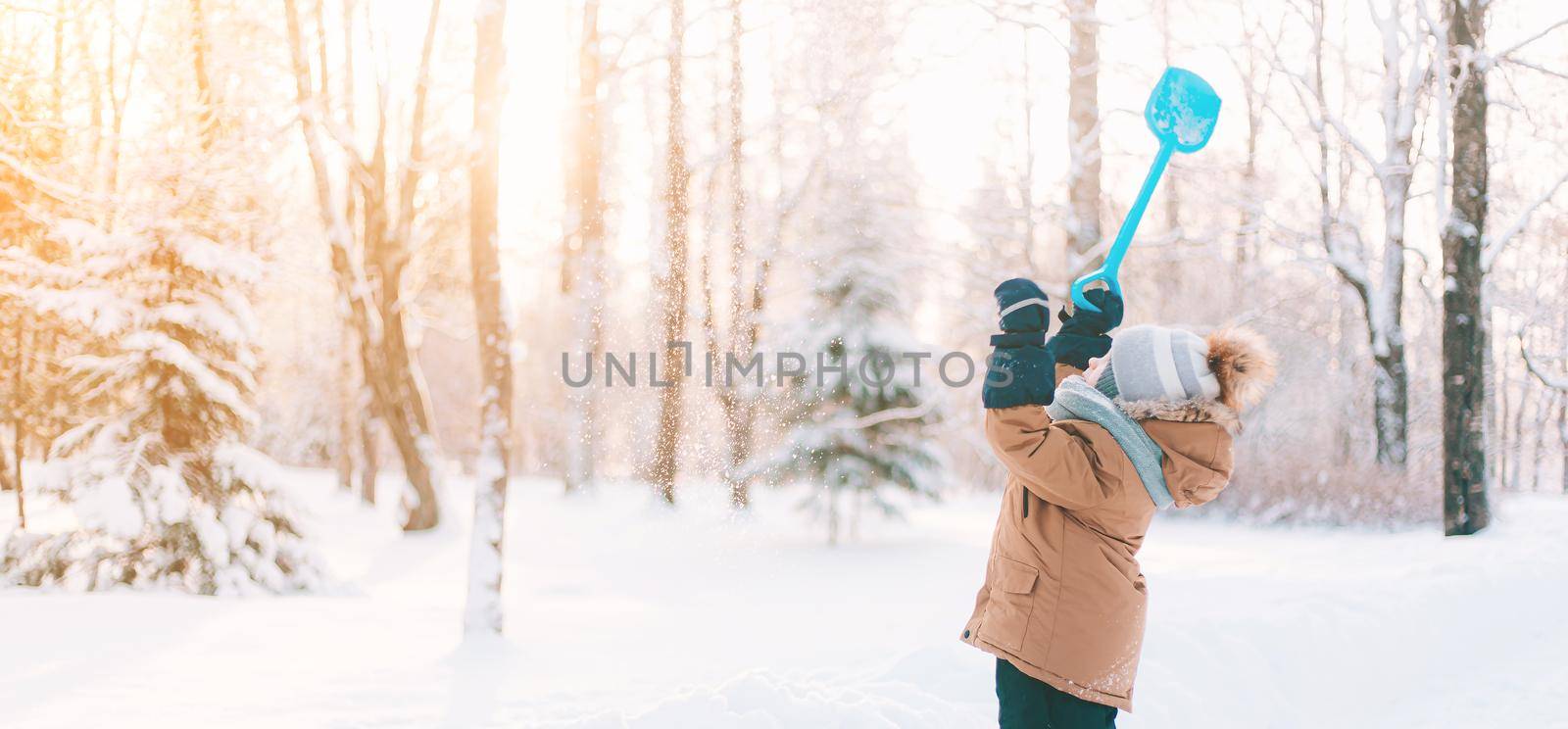 The boy throws snow with a shovel in winter lifestyle . Winter walks. An article about children's winter leisure. by alenka2194