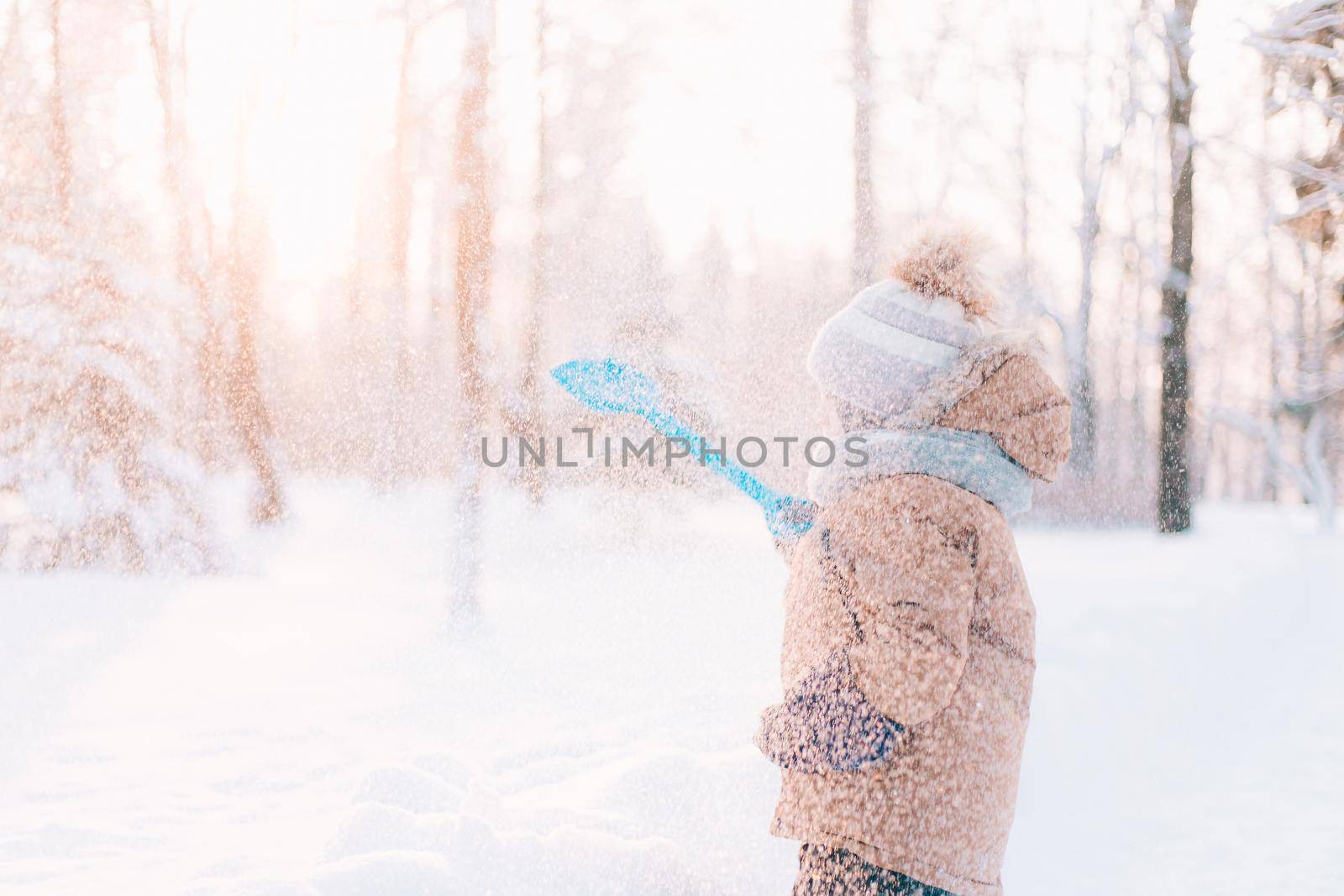 The boy throws snow with a shovel in winter lifestyle . Winter walks. An article about children's winter leisure. by alenka2194