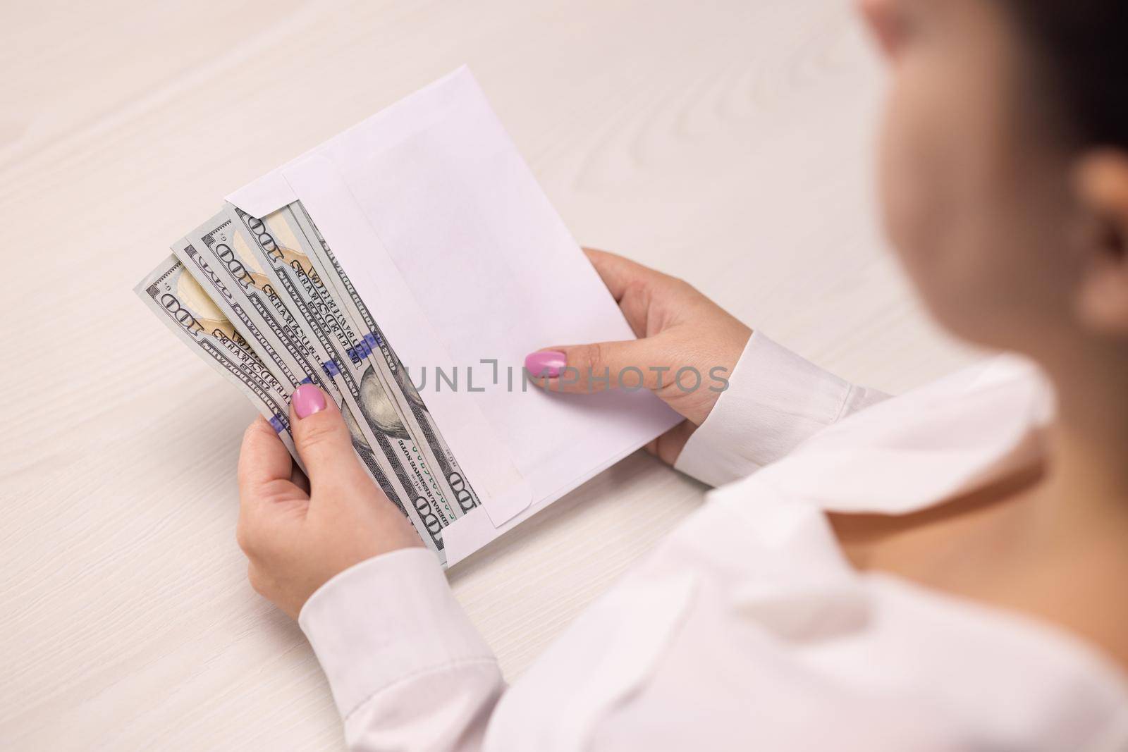 Successful business person takes an envelope with 100 dollar banknotes. Counting hundred dollar banknotes. Illegal deal with money. Corruption. Envelope salary. Tax cheating.