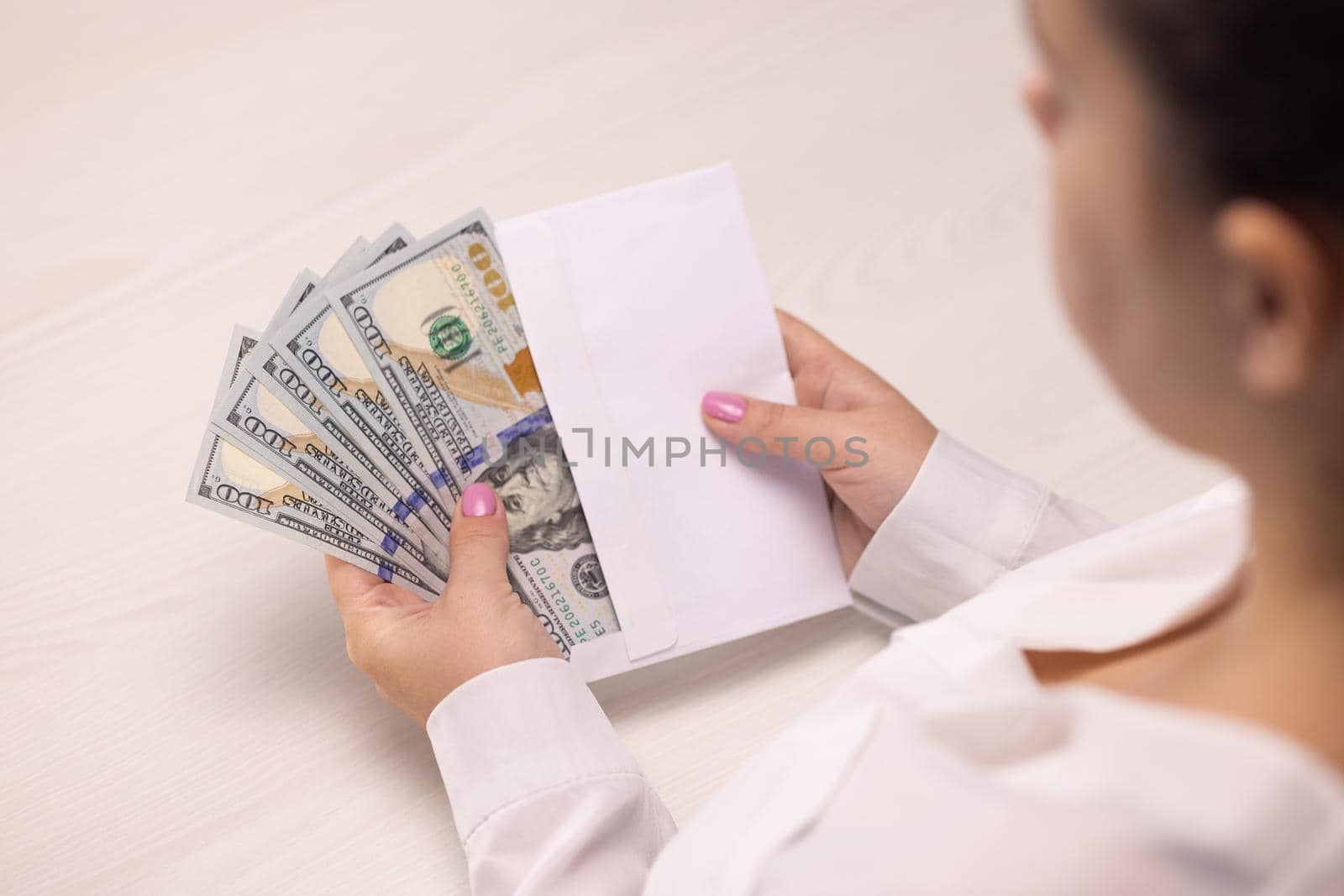 A bundle of hundred dollar banknotes money from the envelope, One hundred banknotes. The concept of corruption and bribery. Female hands checking dollar bills in envelope, illegal salary.