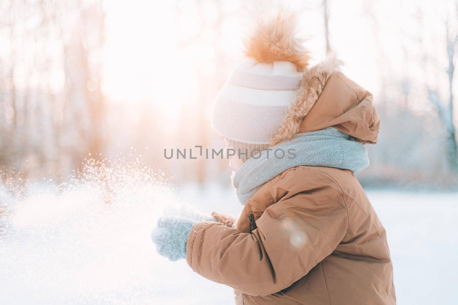 A boy blows snow off his hands winter lifestyle . Winter painting. Snow Park. Cold. Happy childhood