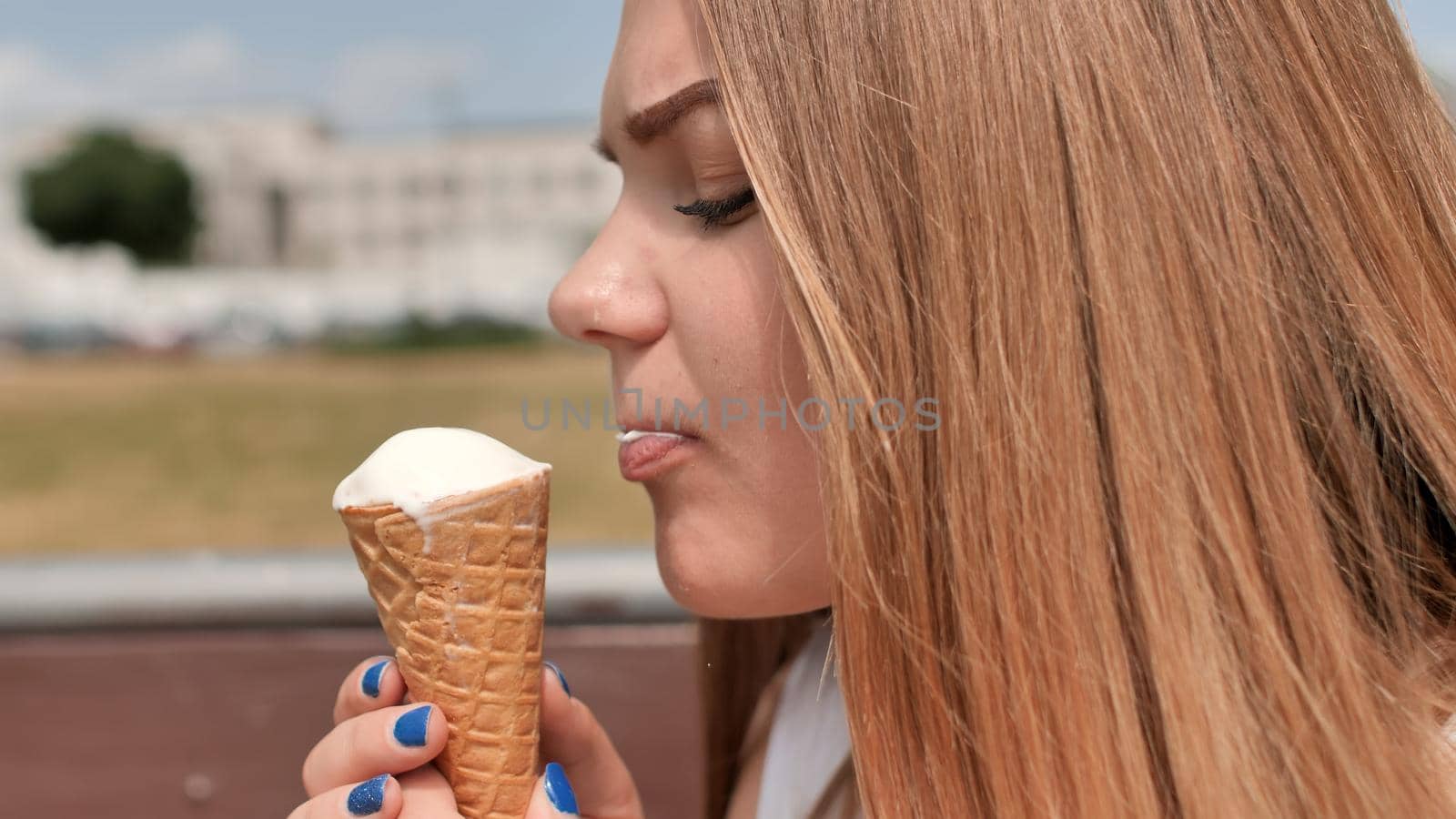 The girl eats an ice cream cone on the street of the city. by DovidPro