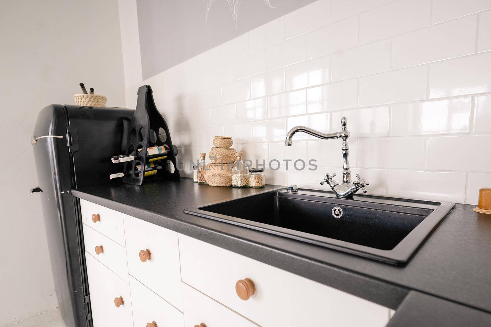 retro style black sink with tap for water in a light kitchen, kitchen furniture, black marble countertop, kitchen cabinet, white tiles on the wall. High quality photo