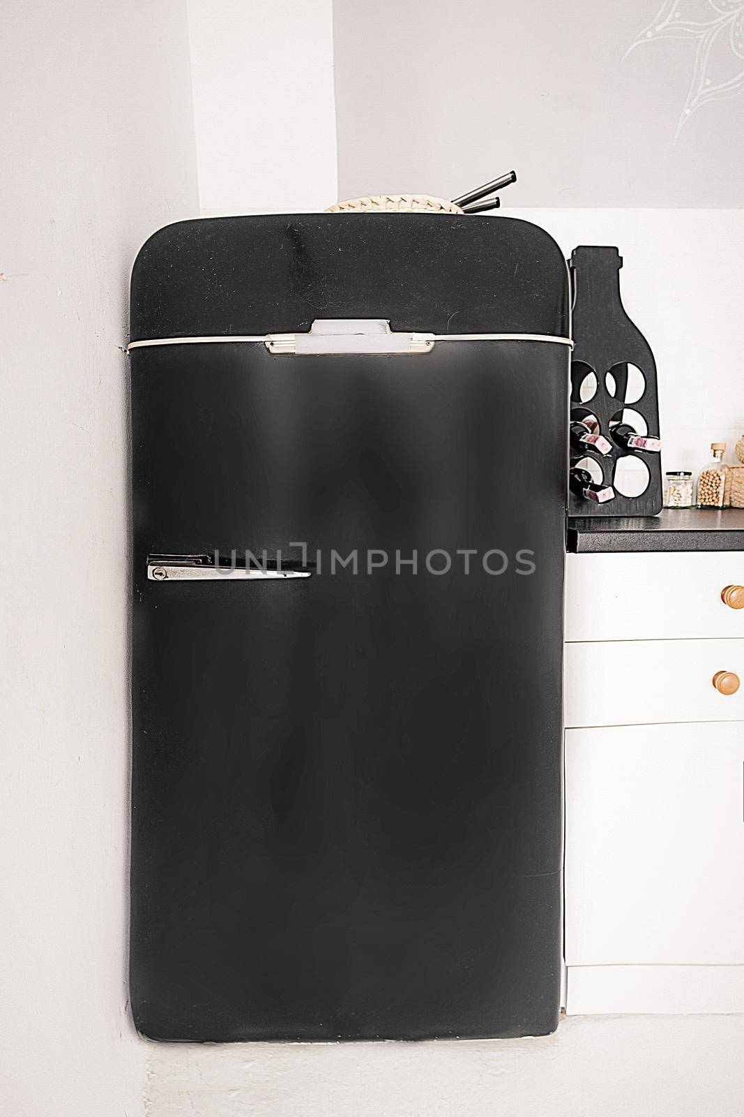 Small Black Retro Refrigerator in White Kitchen, Black Fridge in Vintage Style on White Background. Close-up. High quality photo