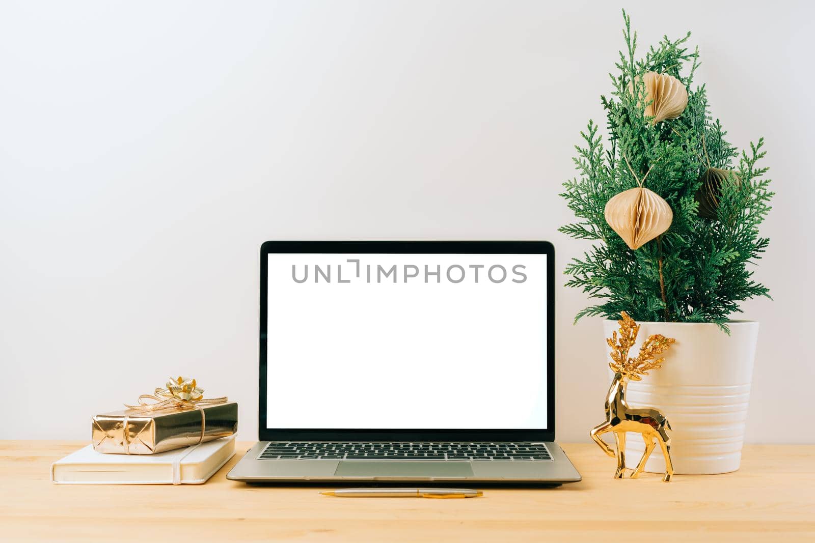 Laptop with mockup blank screen on wooden table with Christmas gift, fir tree on white background. Computer with Mock up and copy space for text.