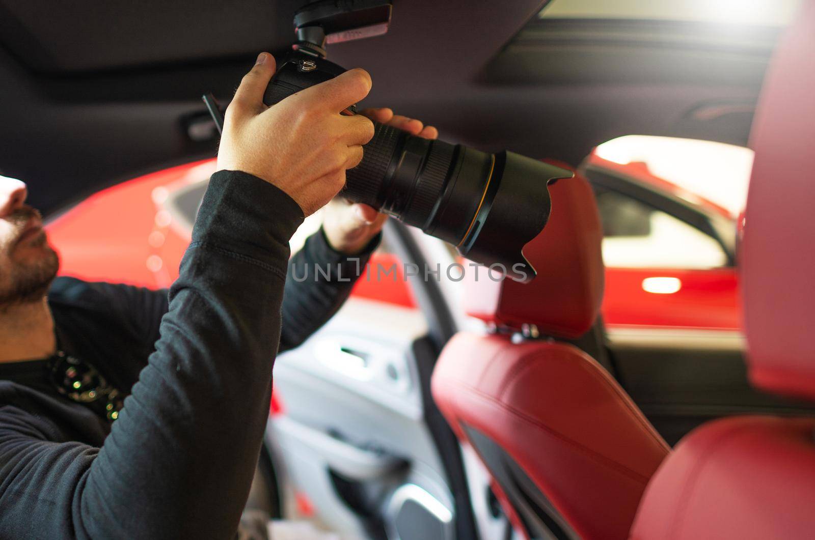 Automotive Professional Photographer with Camera Inside Modern Luxury Vehicle with Burgundy Leather Seats.