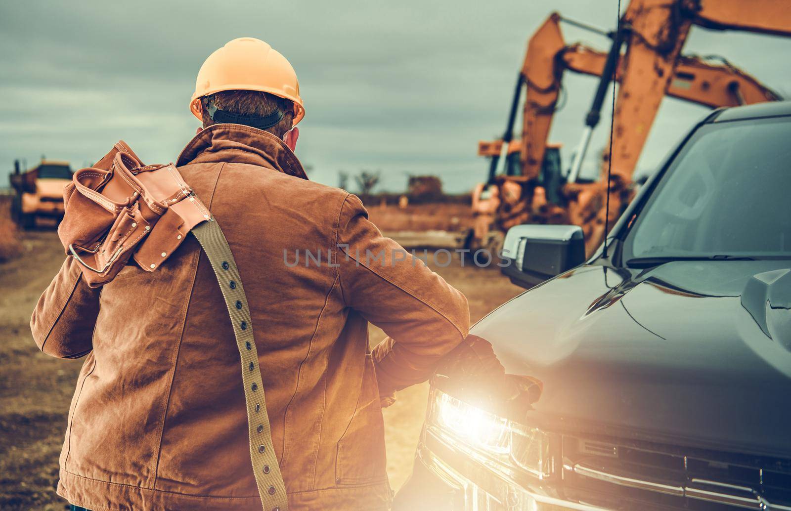 Contractor Worker with Tool Belt on His Shoulder Next to Pickup Truck by welcomia