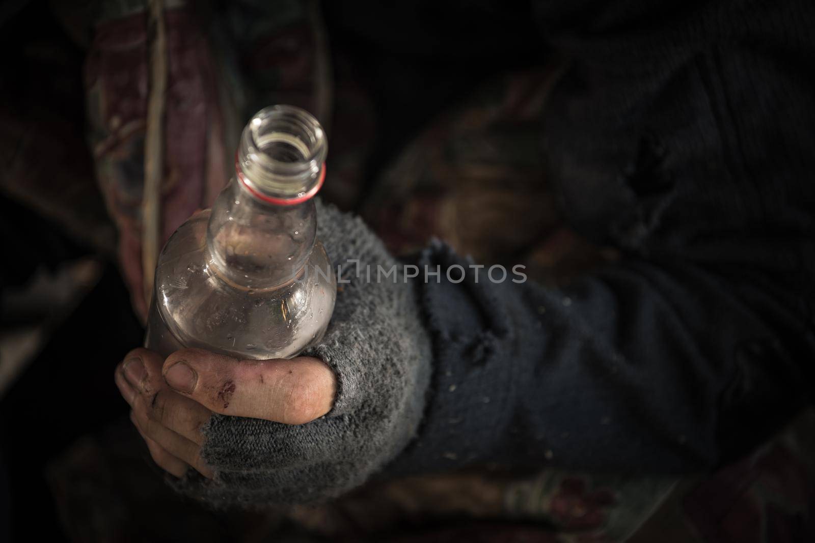 Caucasian Homeless Men Wearing Fingerless Gloves with a Bottle of Vodka Close Up.