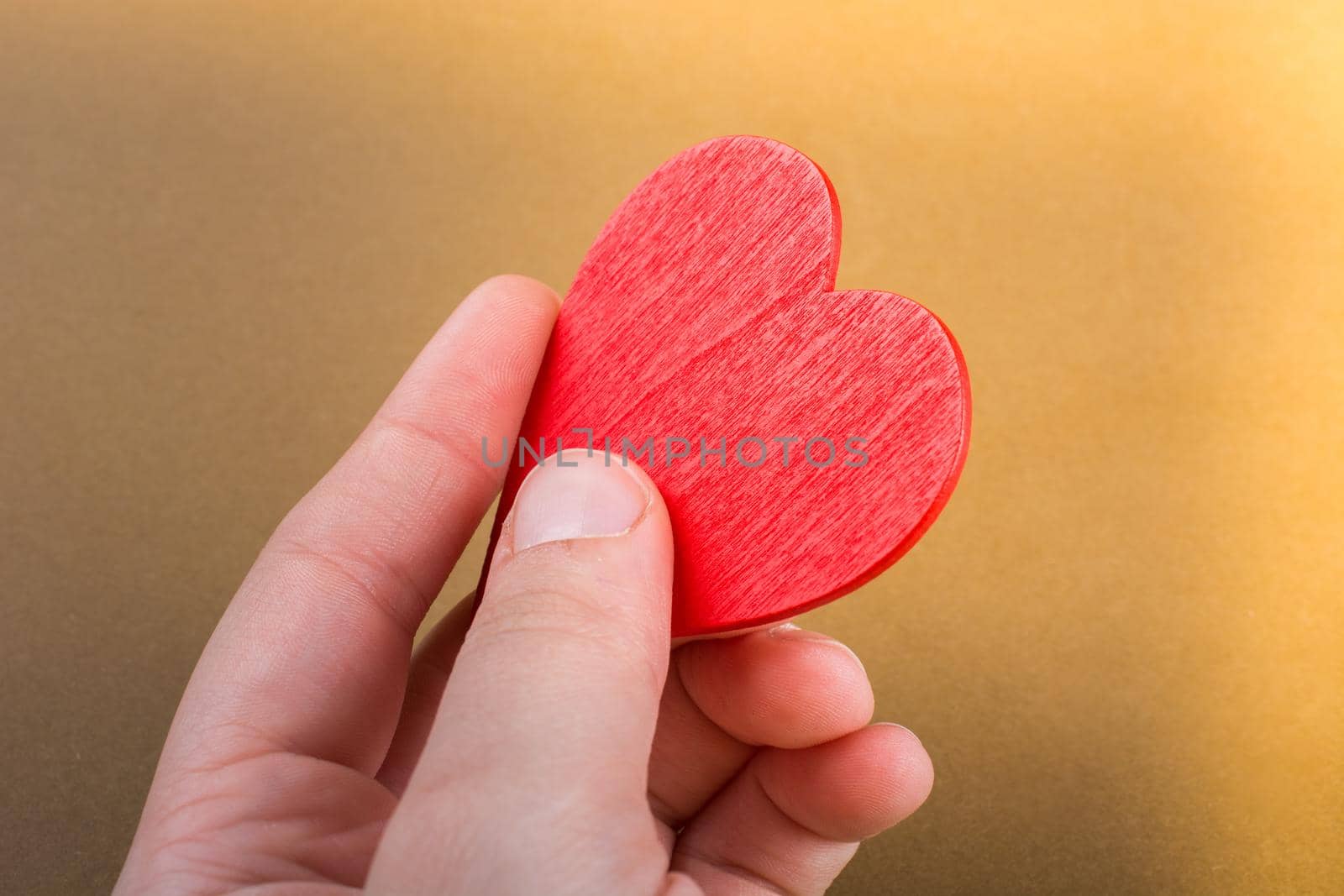 Red color heart shaped object in hand  on dotted paper