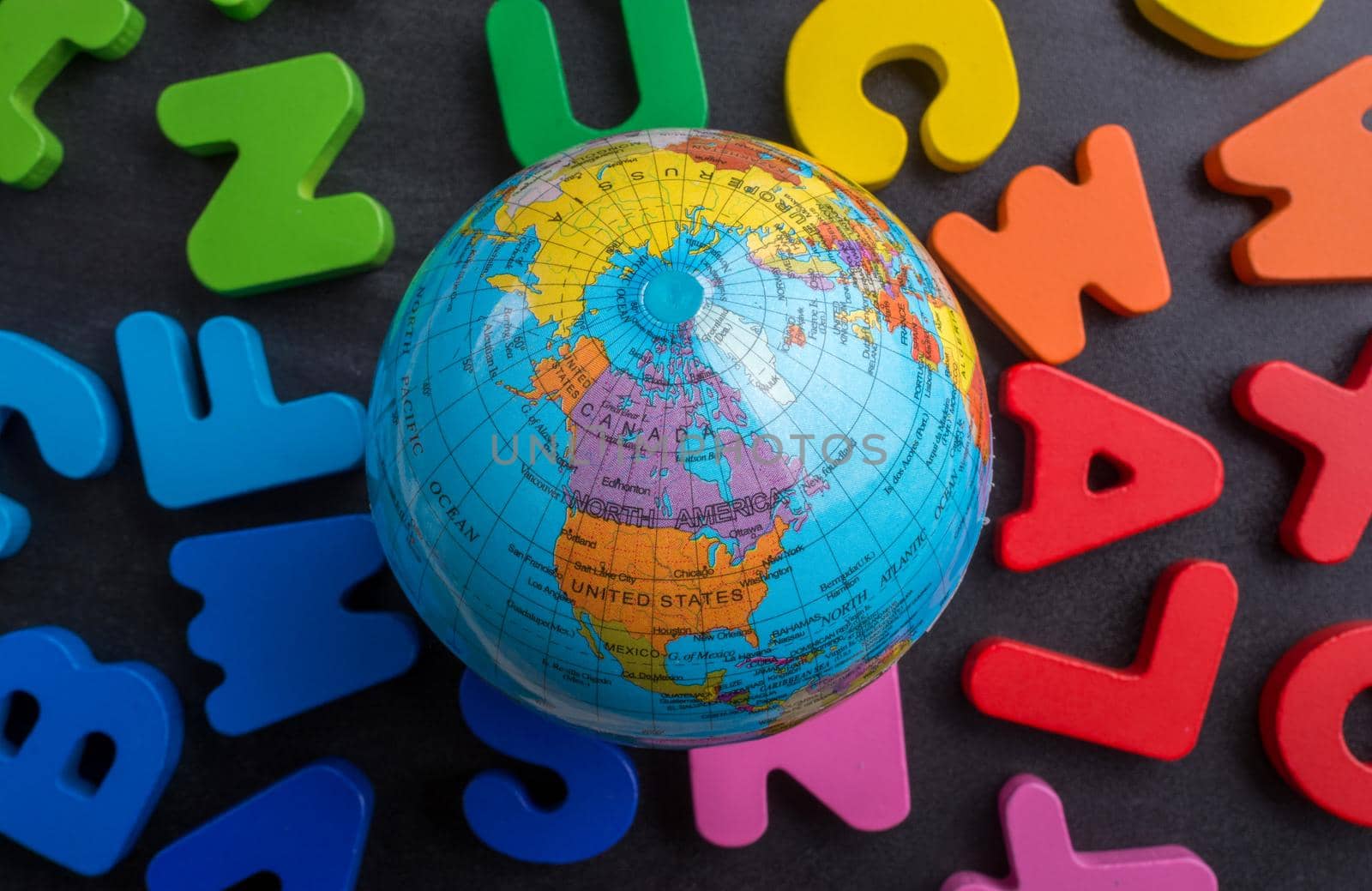 Earth globe model on colorful letters on a black background