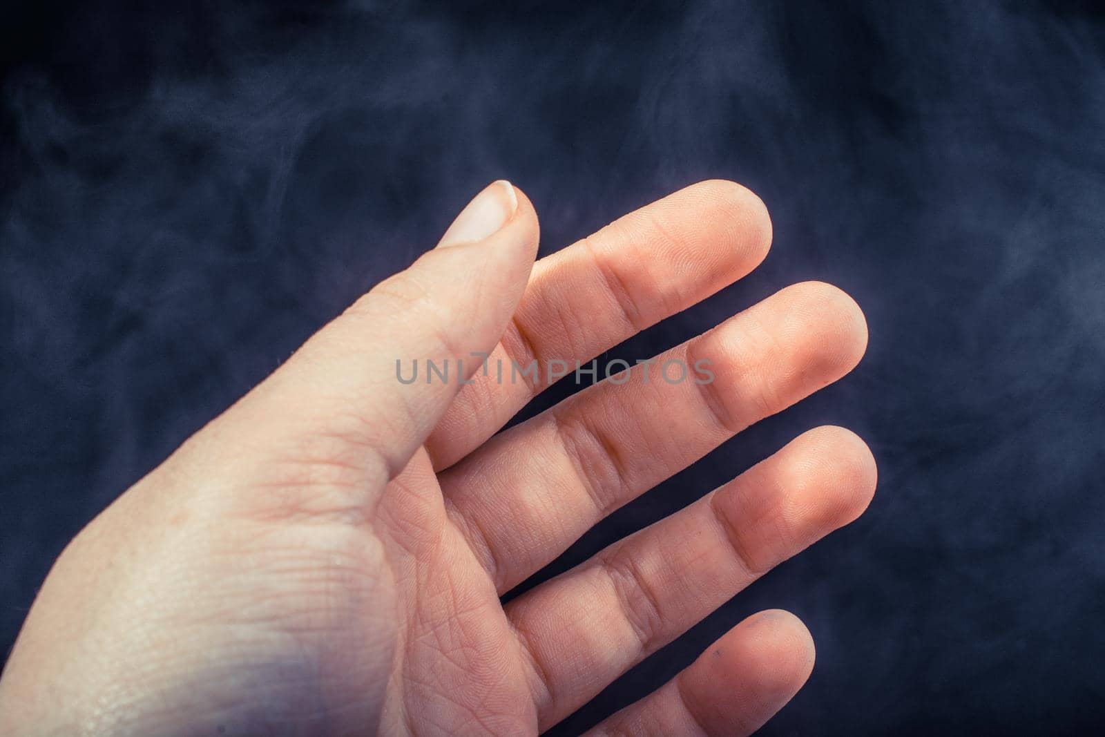 Hand making a gesture on black smoky background by berkay