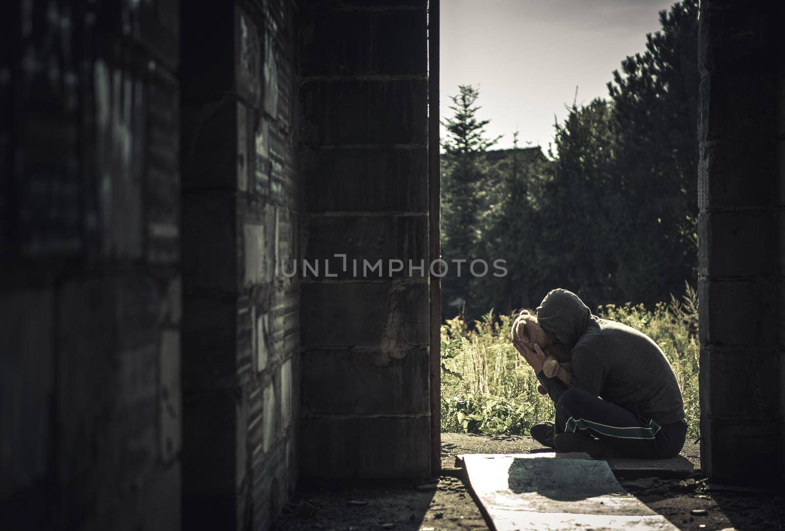 Men with Mental Disorder Hugging His Teddy Bear Toy in Front of House Ruins. Homelessness and Mental Sickness Concept Theme.