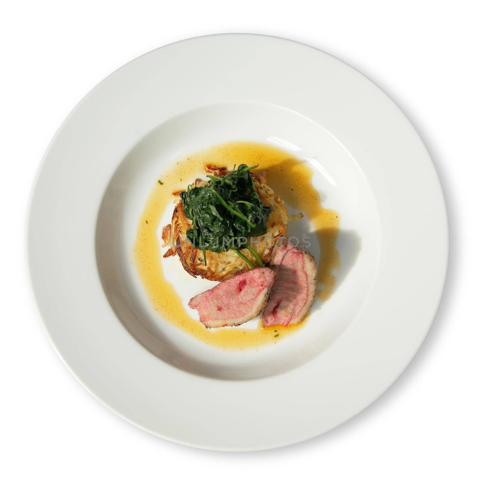 A white diner plate with lamb loin spinach and potato rosti