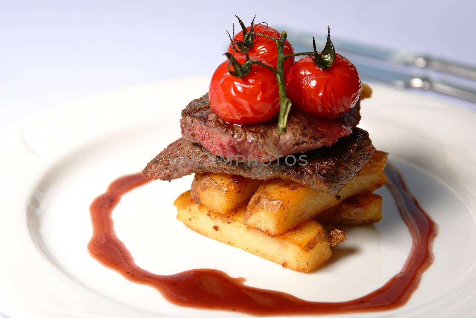 A beef steak with tomatoes and french fries