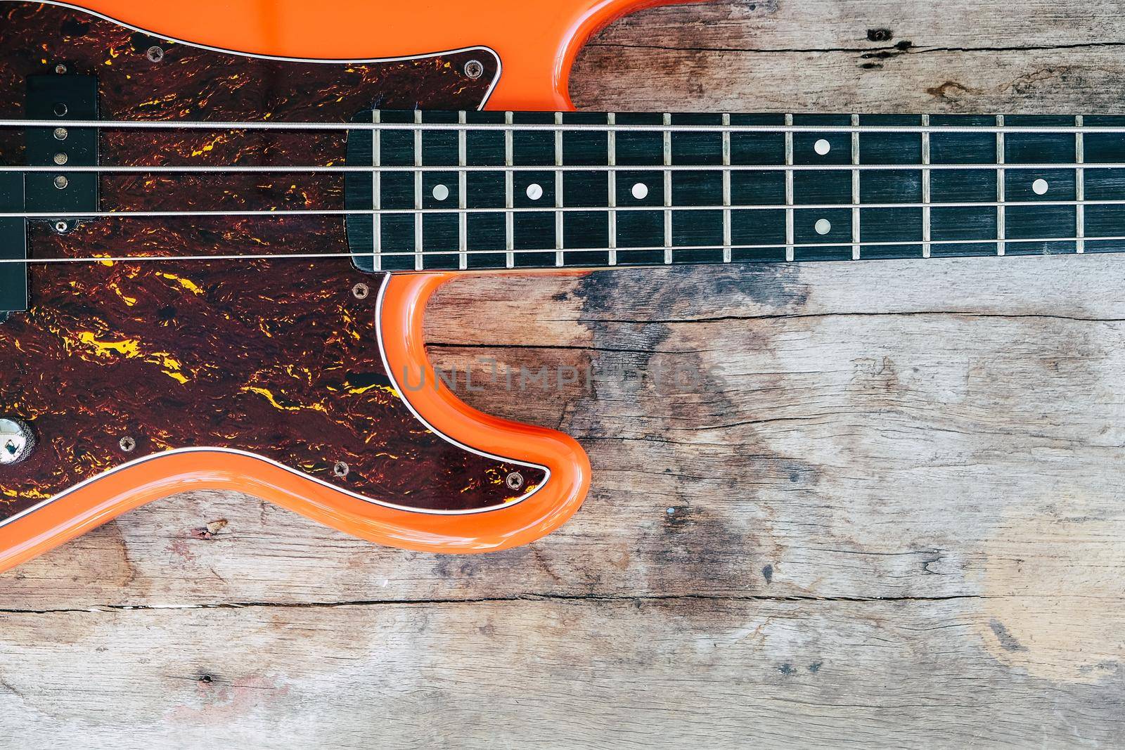 orange electric bass guitar on wood background by ponsulak