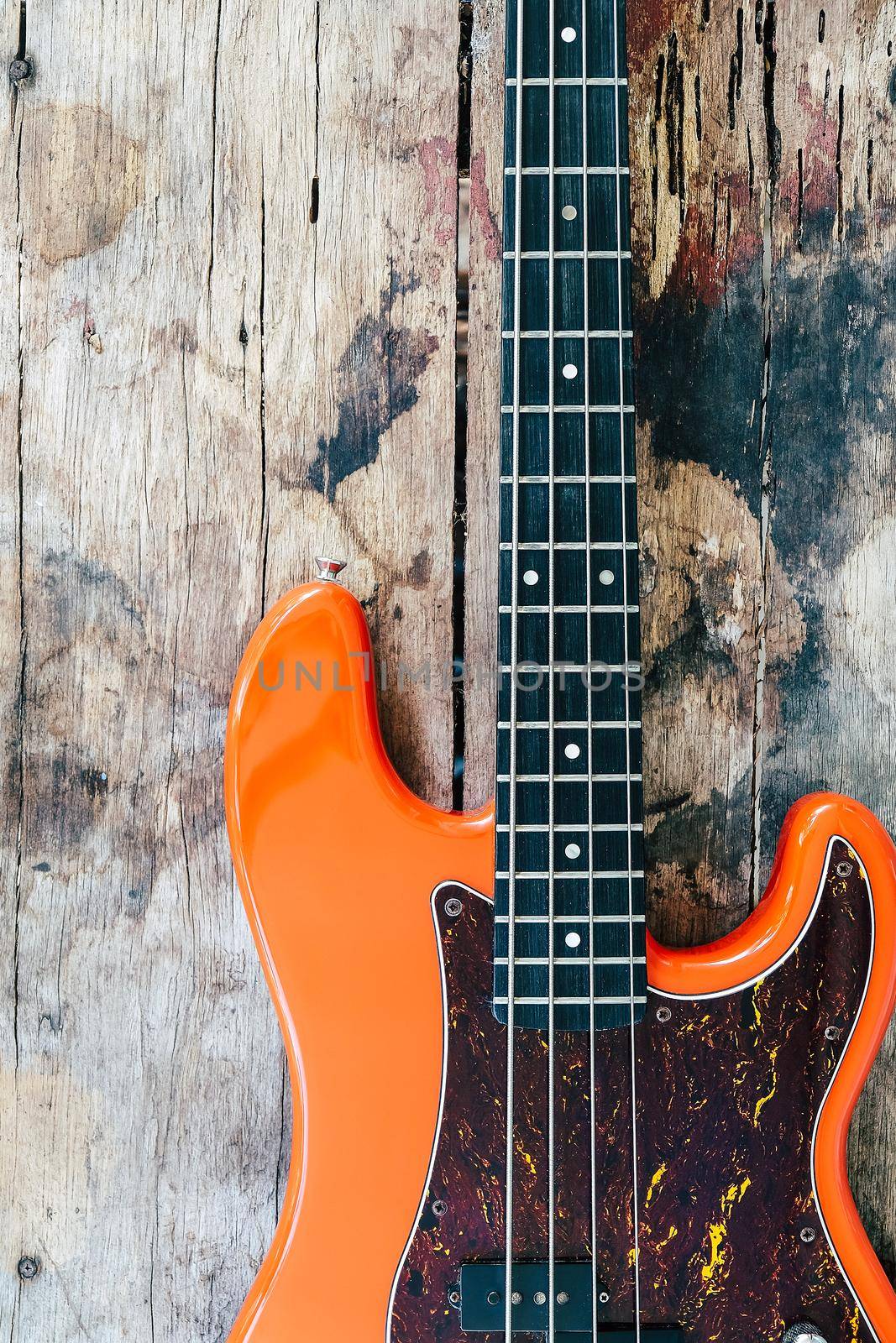 orange electric bass guitar on wood background by ponsulak