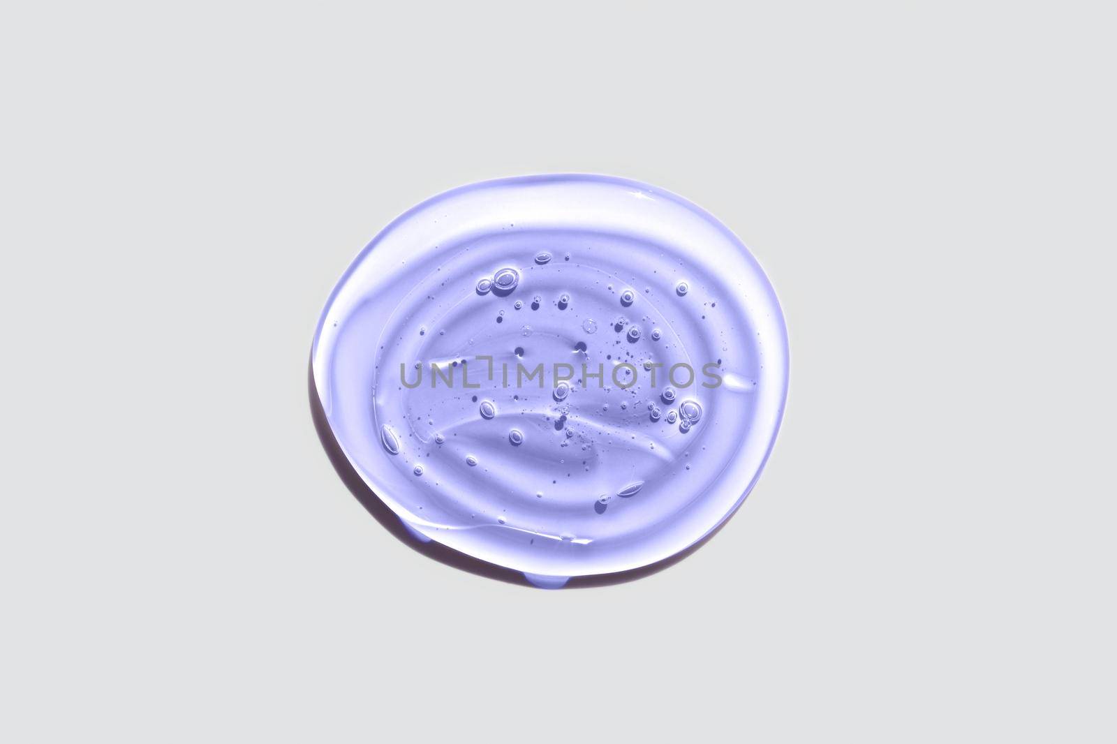 Light purple or violet transparent oval gel drop isolated on white background. Top view. Virus protection or cosmetics concept. Face Serum texture Trendy banner with 2022 color of the year very peri.